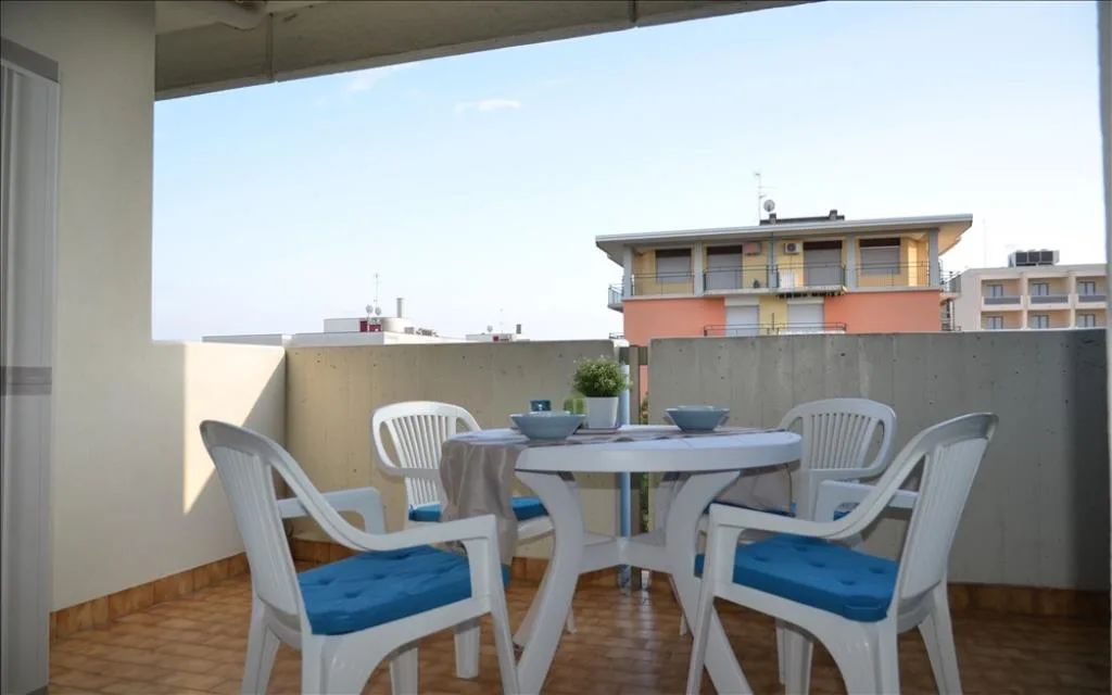Balcone arredato con tavolo e sedie bianche